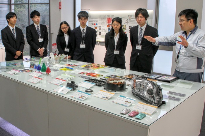 First-term program students listening to production explanation in front of a display booth at DIC Research Institute, which is responsible for foundation element technology and new product development.