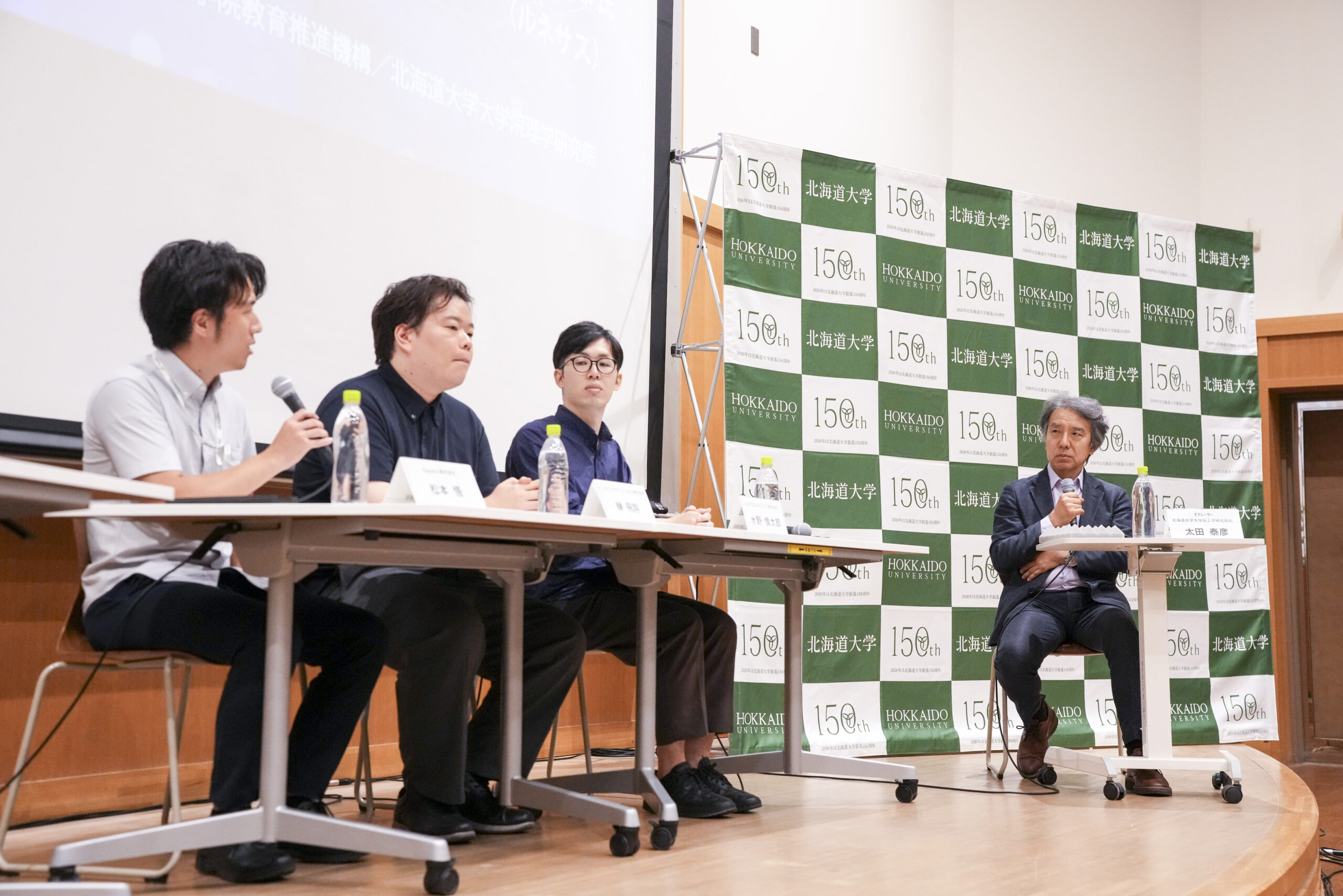 太田教授(北海道大学大学院工学研究院/半導体フロンティア教育研究機構)の鋭い問いかけによって、登壇者から本音が飛び出し、参加した学生も話に引き込まれていった。右からモデレーターを務めた太田教授、水野氏(ルネサスエレクトロニクス株式会社)、榊氏(ソニーセミコンダクタソリューションズ株式会社)、松本氏(Rapidus株式会社)。